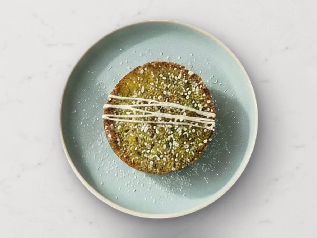 A Citrus Matcha mochi cake with white icing drizzle on a sage plate