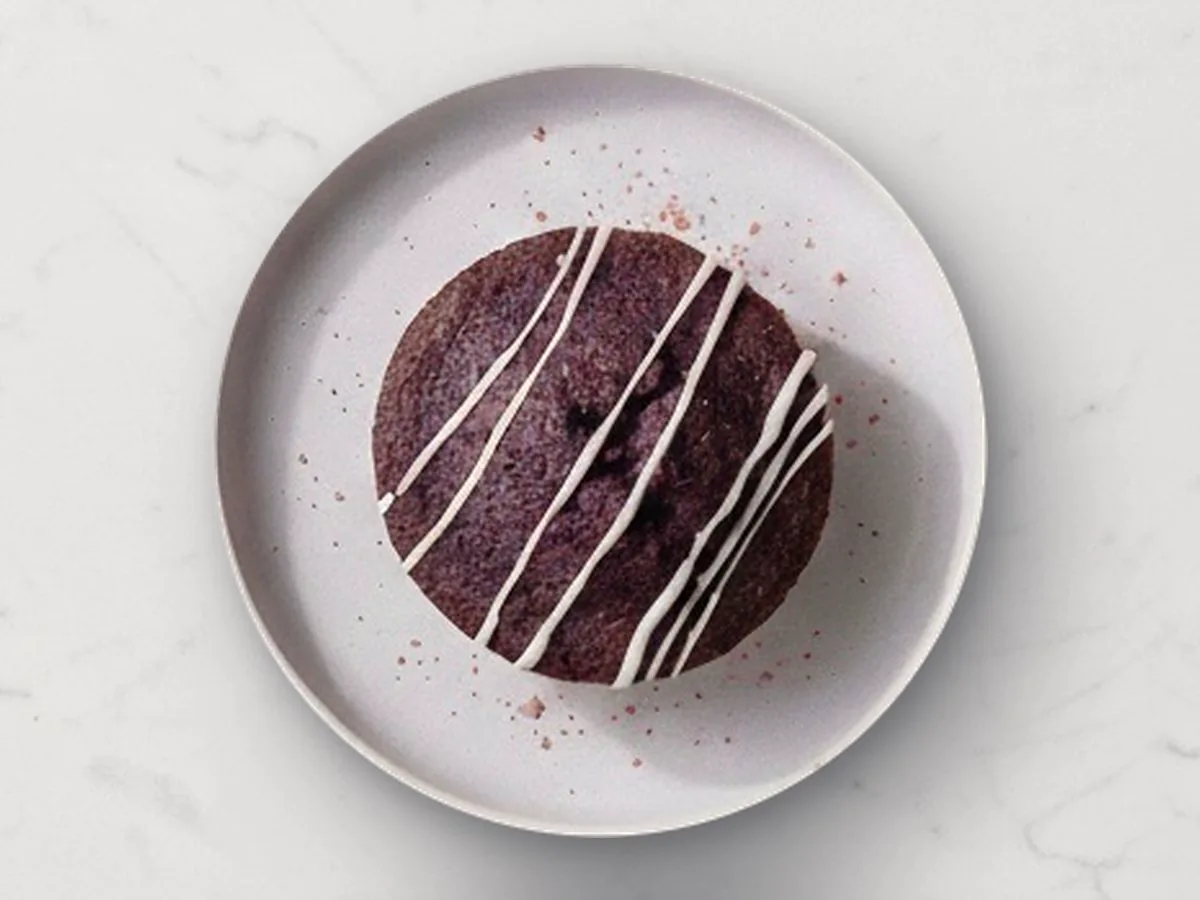 A Velvety Ube mochi cake with icing drizzle on a lilac plate